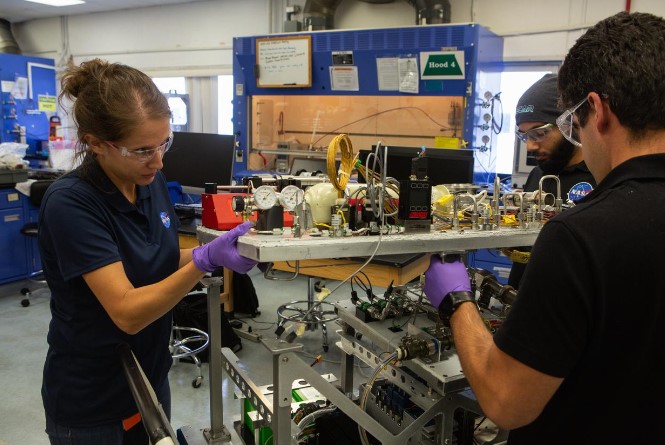 Principal investigator Dr. Annie Meier and engineers Malay Shah and Jaime Toro assemble the flight hardware for NASA’s OSCAR trash-to-gas conversion system on Oct. 10, 2019, at Kennedy’s Space Station Processing Facility.