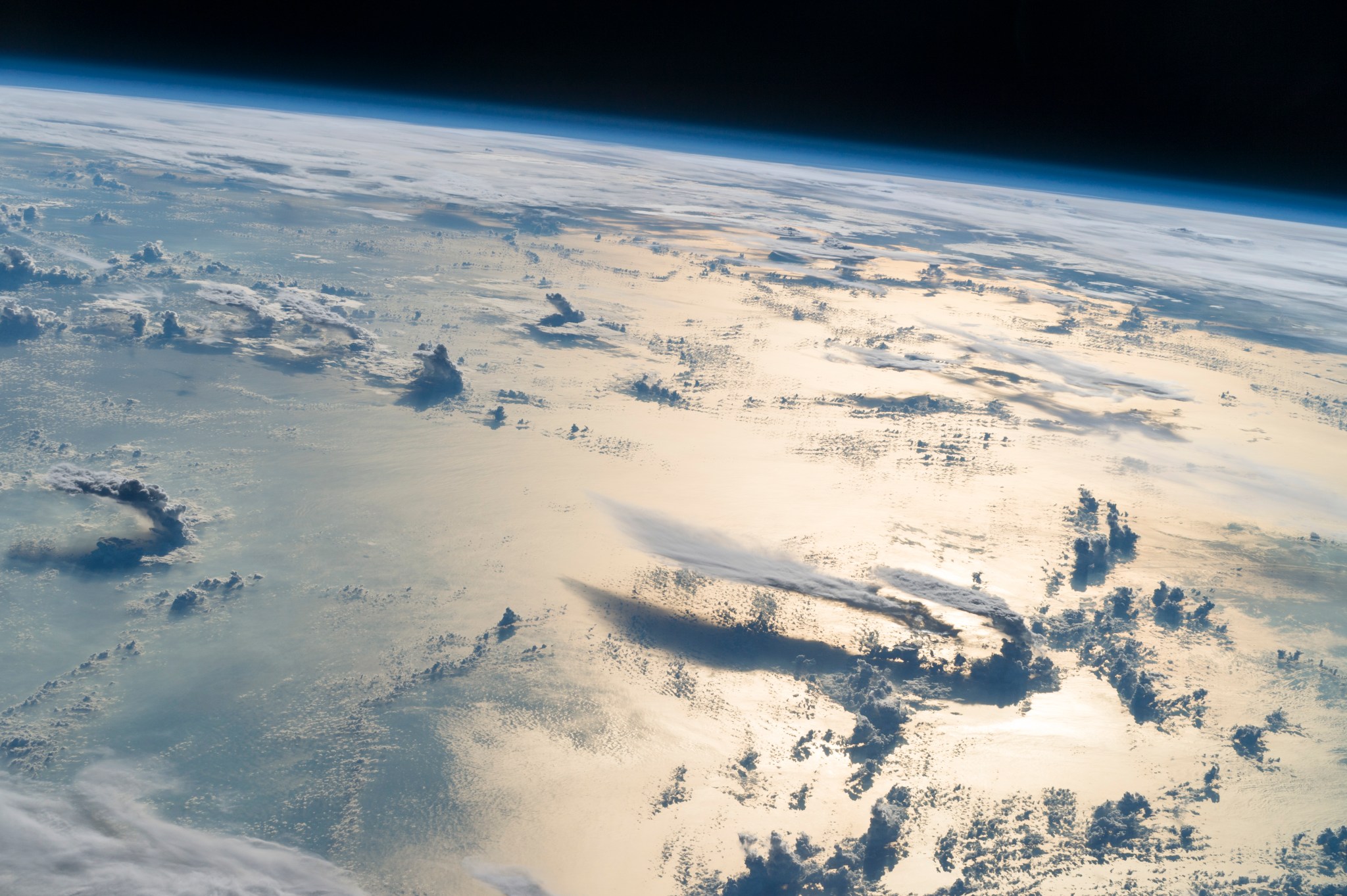 An astronaut image of clouds casting their shadows on Earth's oceans.