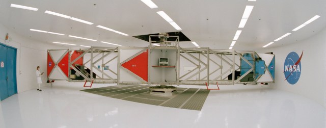 A woman stands next to a large centrifuge