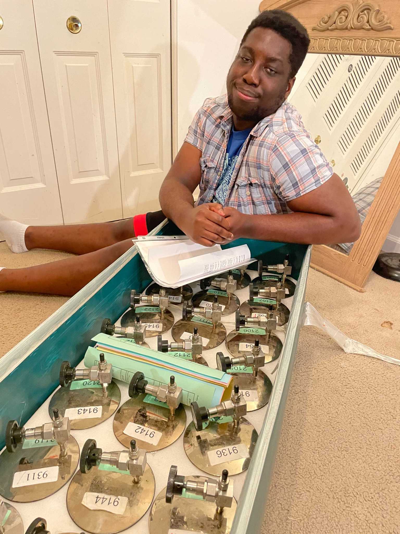 An intern sits near a box of canisters.