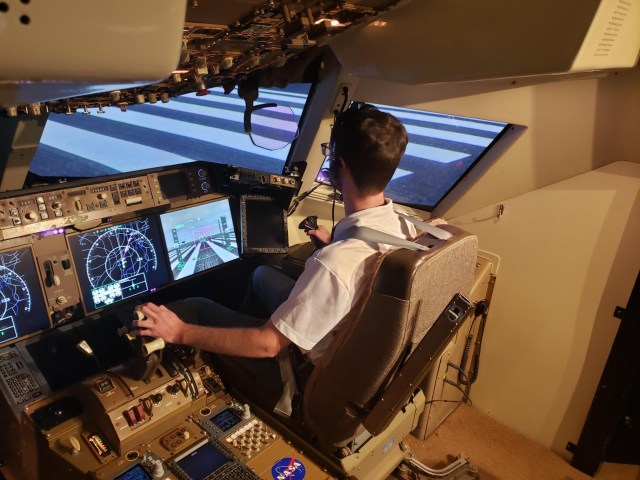 Man sitting in chair using flight simulation software.