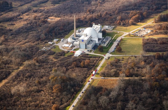 Aerial view of the Neil A. Armstrong Test Facility, with a truck carrying Orion Spacecraft visible in the foreground approaching the facility.