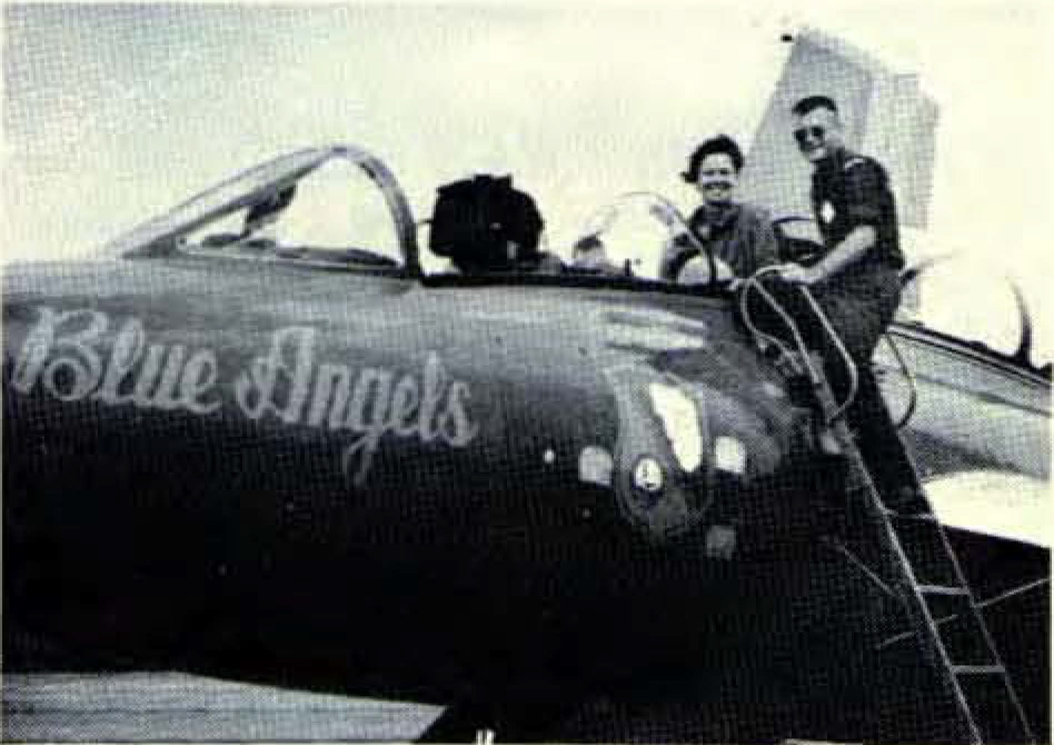 Woman in flight suit gets into jet seat.