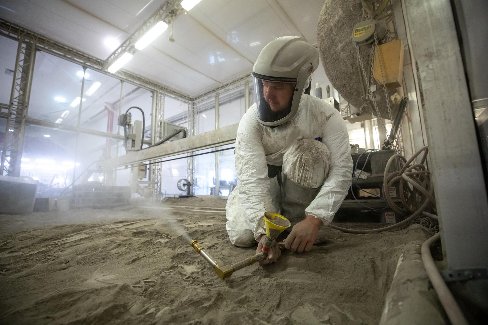 Austin Langton, a researcher at NASA's Kennedy Space Center in Florida, creates a fine spray of the regolith simulant BP-1, to perform testing with a Millimeter Wave Doppler Radar at the Granular Mechanics and Regolith Operations Lab on July 16, 2021. 