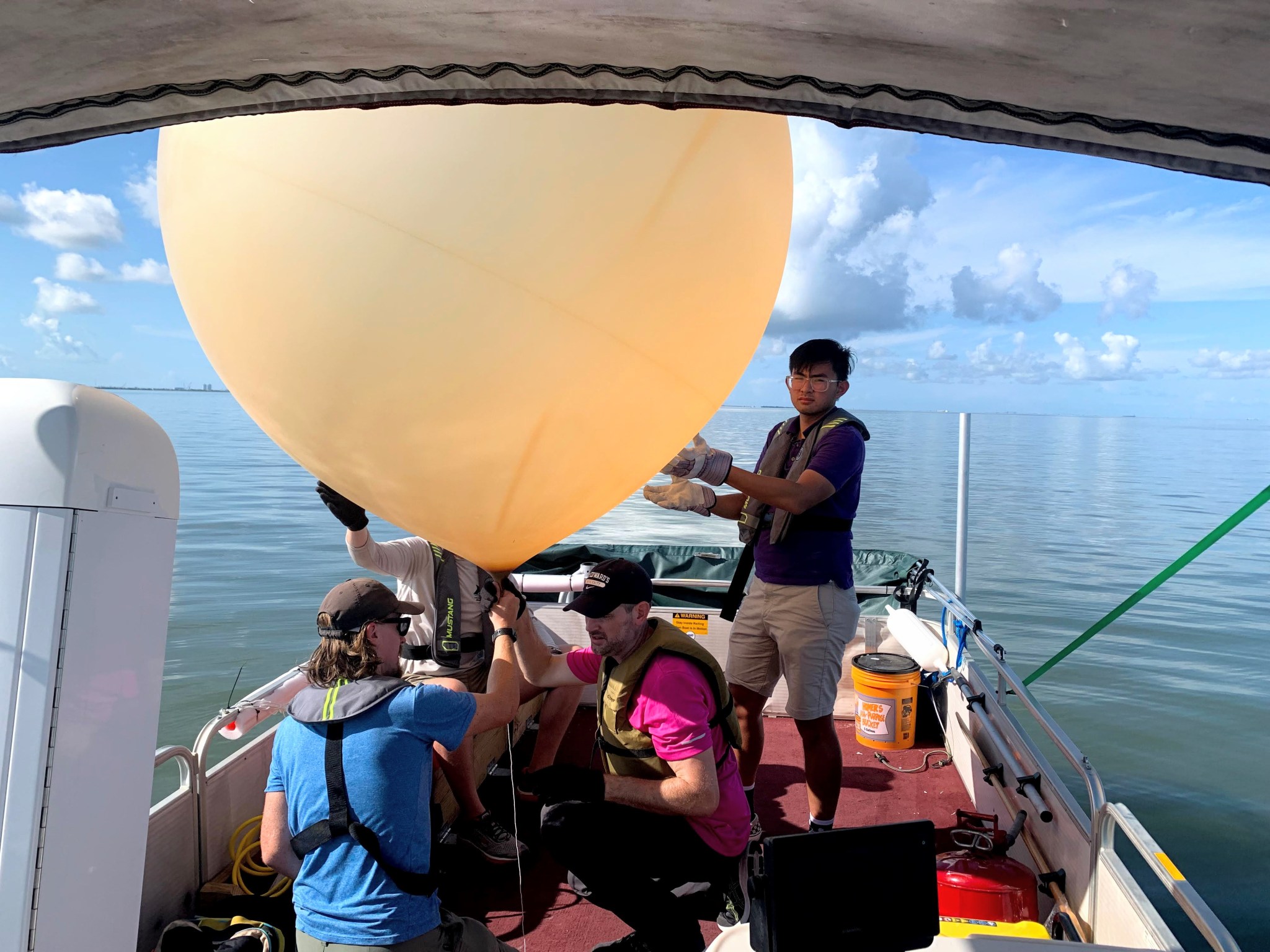 TRACER-AQ researchers launch a balloon sonde from a boat.