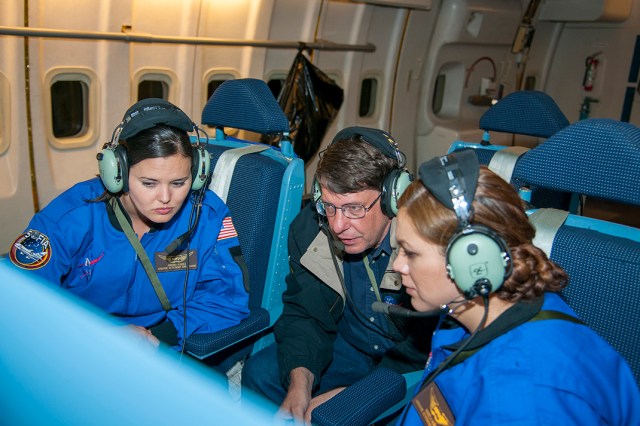 Three people inside of the SOFIA aircraft during a flight.