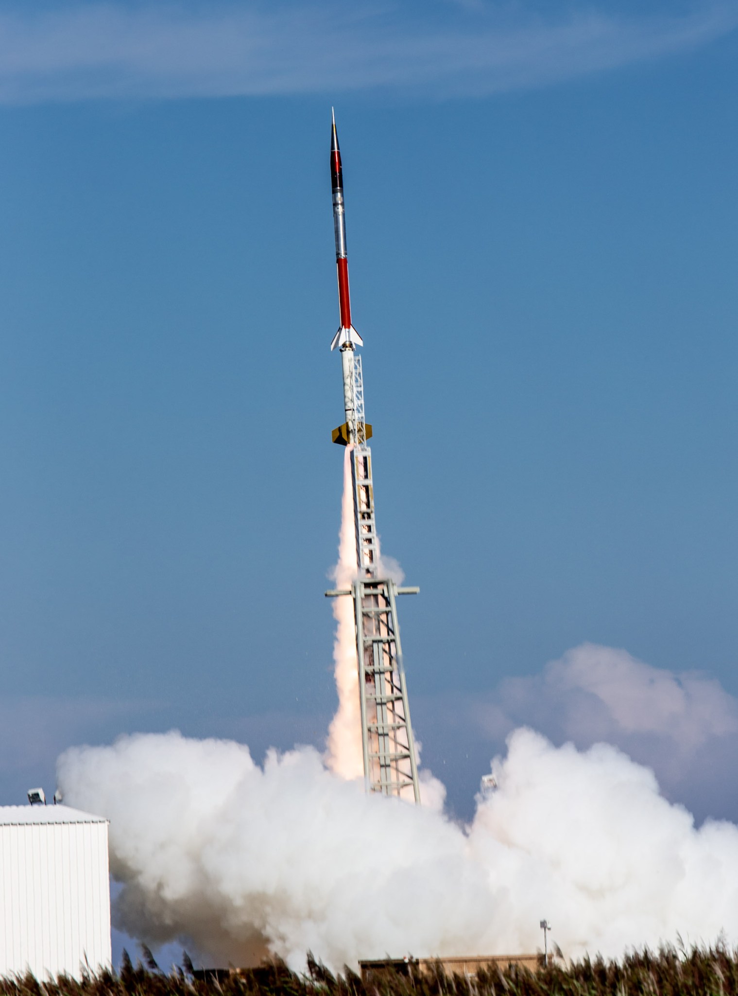 sounding rocket launching with plume of smoke underneath.