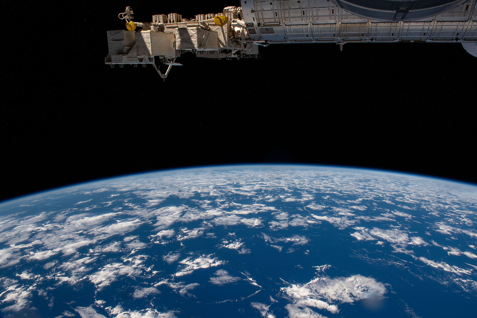 Arial view from space looking down at earth, view of the curve of the earth with mostly water and clouds below 