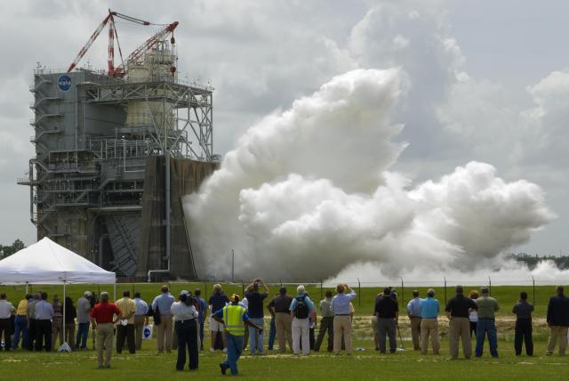A crowd of people watch from afar during the final hot fire test of the Space Shuttle main engine