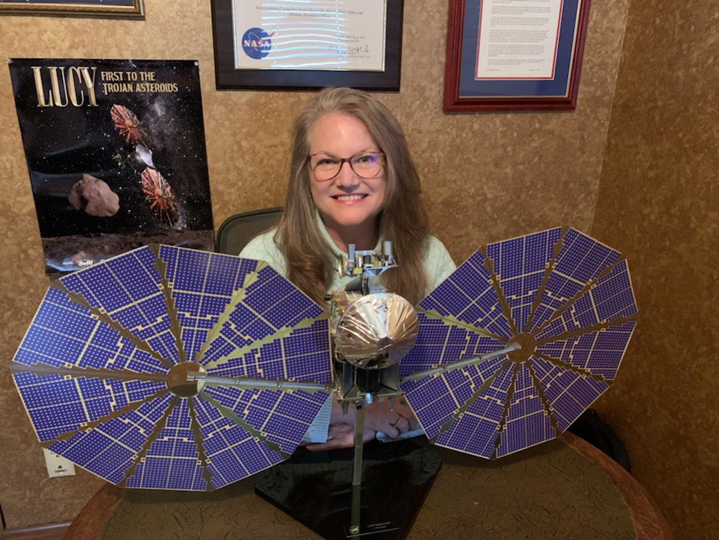 Sherry Jennings, mission manager for the Lucy mission, poses next to a model of the Lucy spacecraft.
