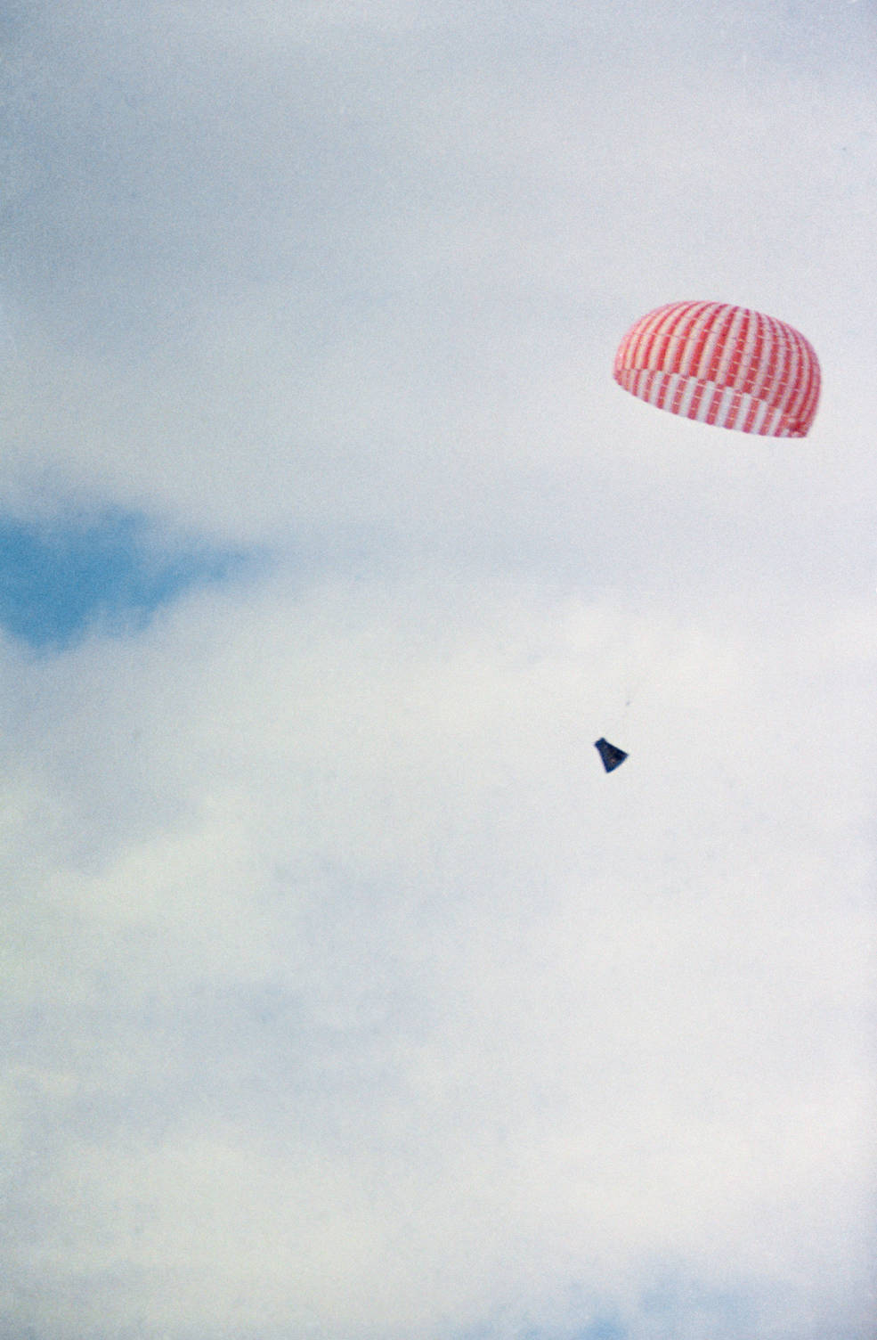 The Gemini XII spacecraft dangles from a parachute as it returns to Earth from space