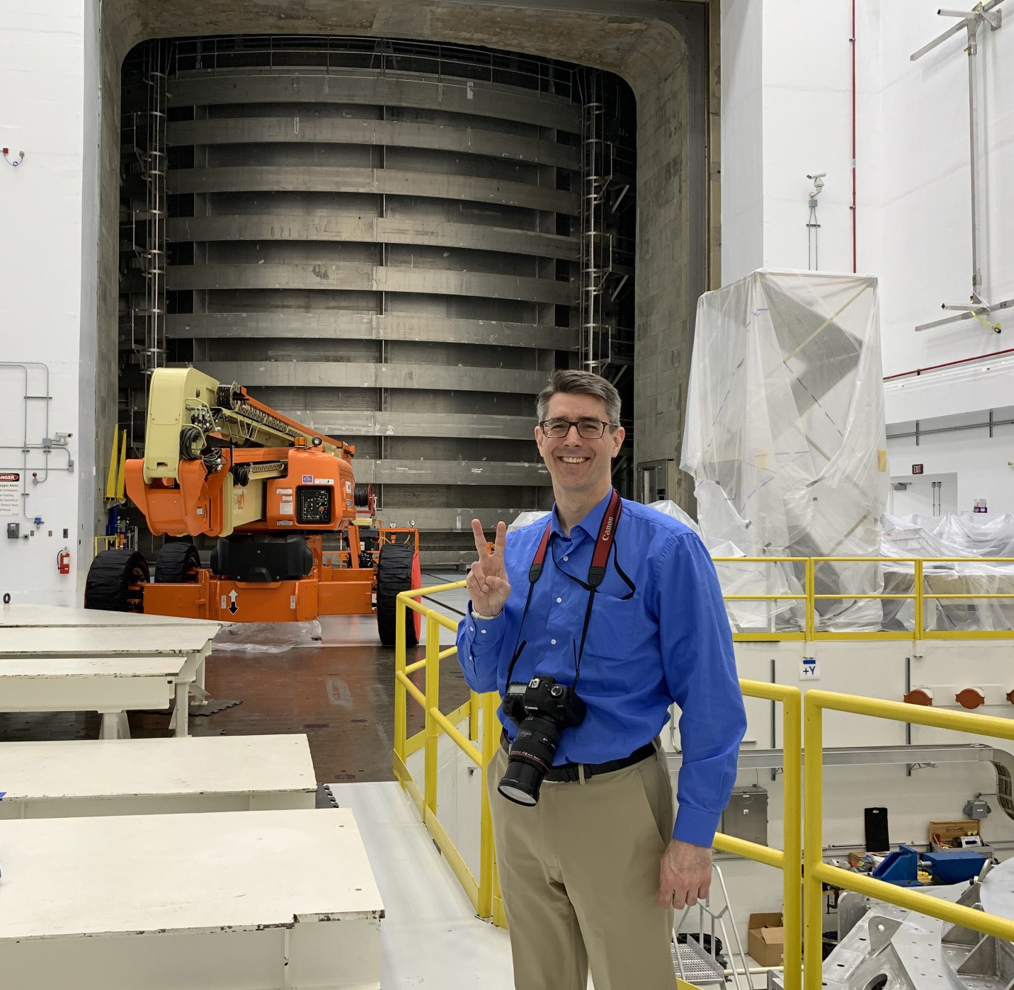 Man facing camera and giving the peace sign outside a NASA vacuum chamber.