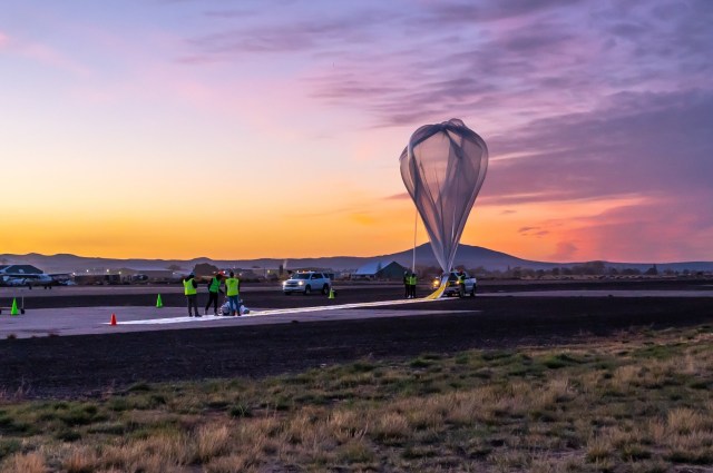 Ground crew inflate a high-altitude balloon at dawn.