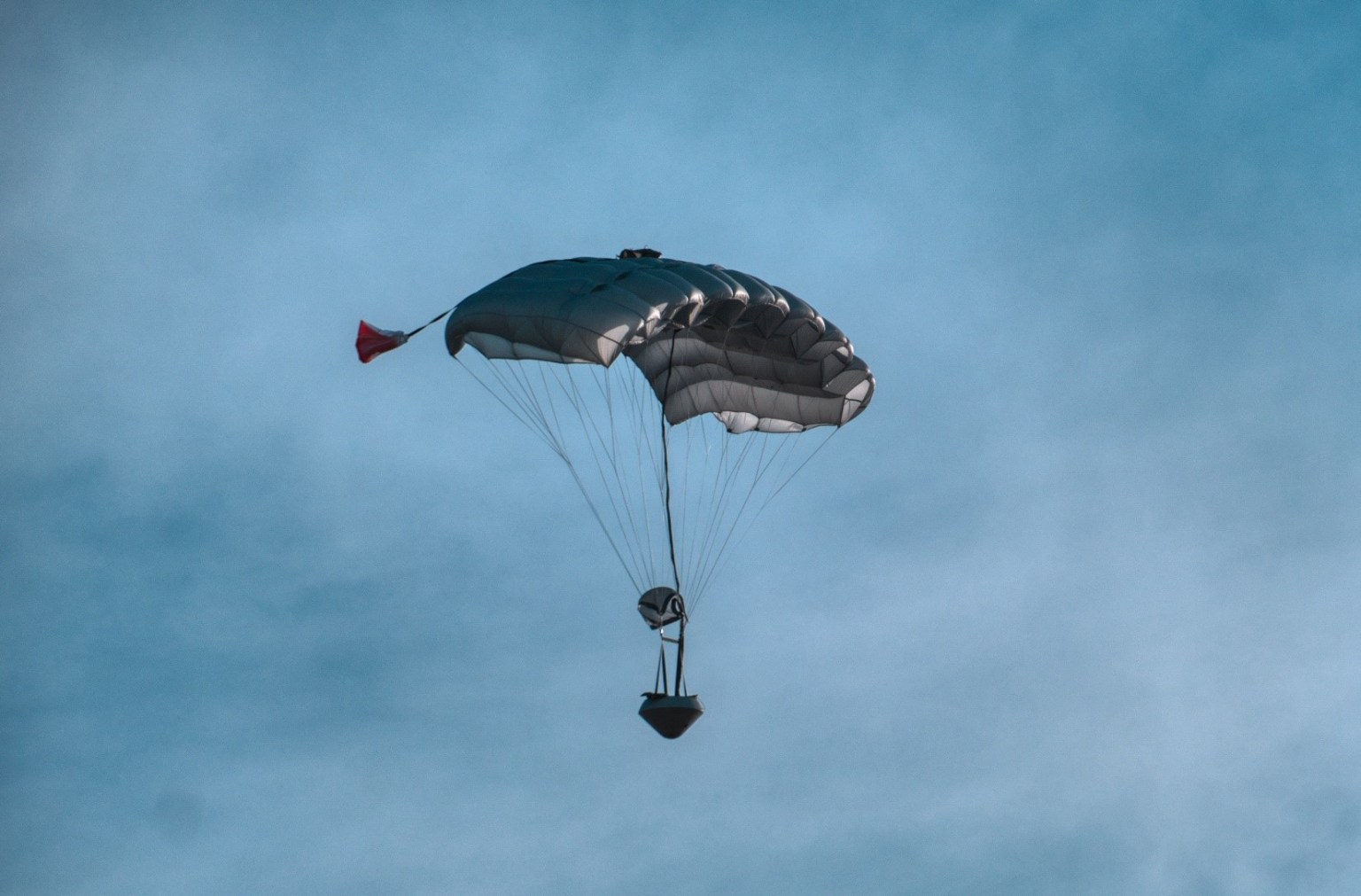 Deployed parachute and payload against a cloudy sky