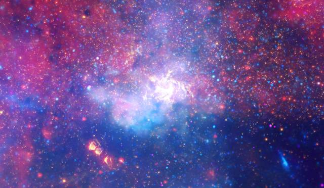 An enormous swirling vortex of hot gas glows with infrared light, marking the approximate location of the supermassive black hole at the heart of our Milky Way galaxy.