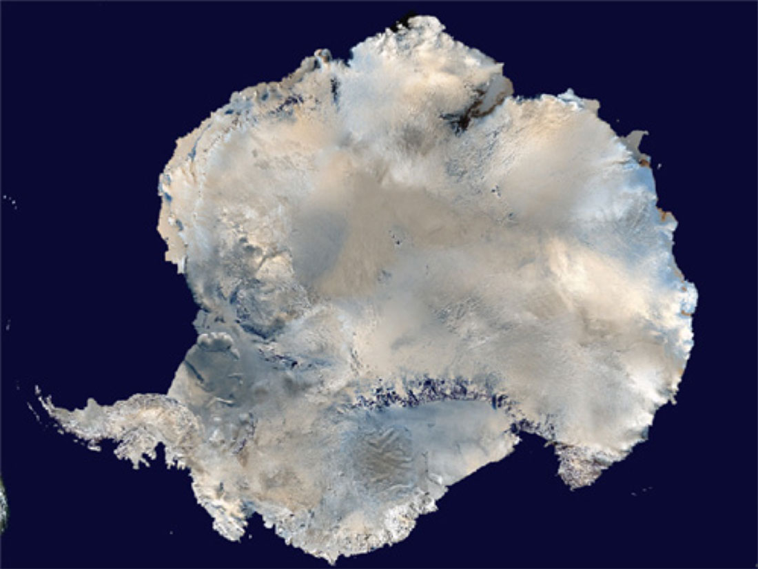 Top down view of Antarctica, with blueish shadows and light brown peeking through the snow, against a dark blue ocean.