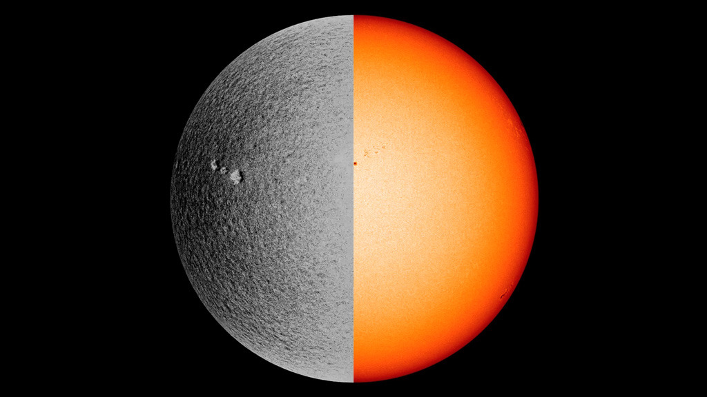 The Sun is shown with the left hemisphere in gray and the right hemisphere in orange. Three white spots appear to the upper left of center on the left, gray side. A few small, black sunspots appear to the upper right of center on the right, orange side.