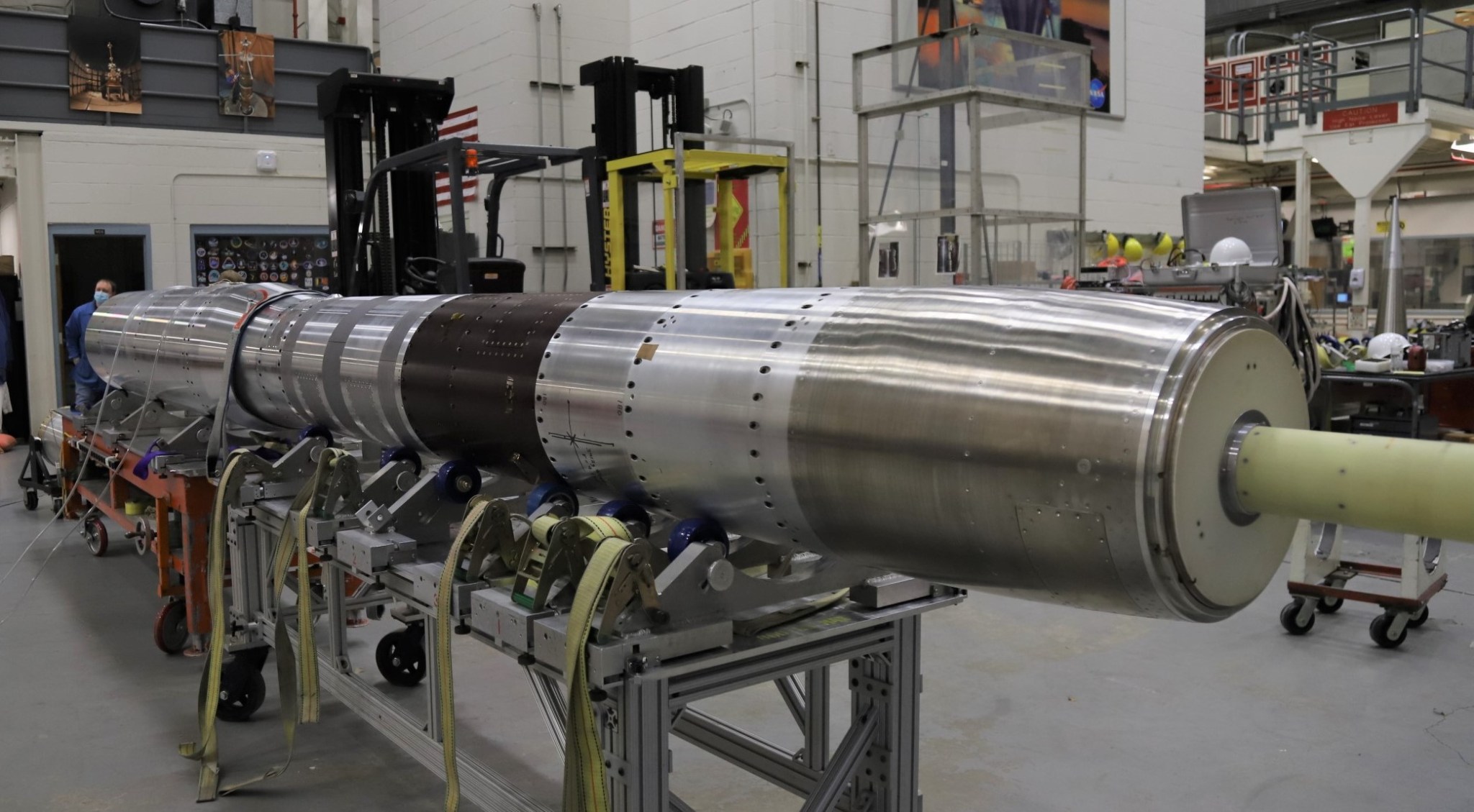 A metal payload section of a sounding rocket sits on a roller table.