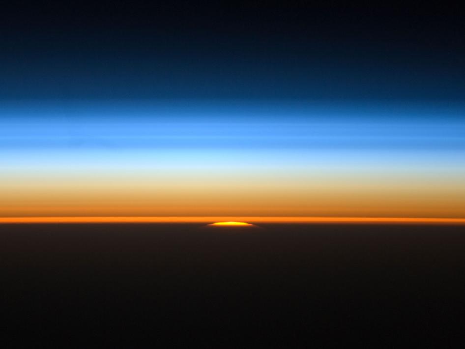A black band across the bottom with the sky, fading from orange (below) to blue (above) overhead.
