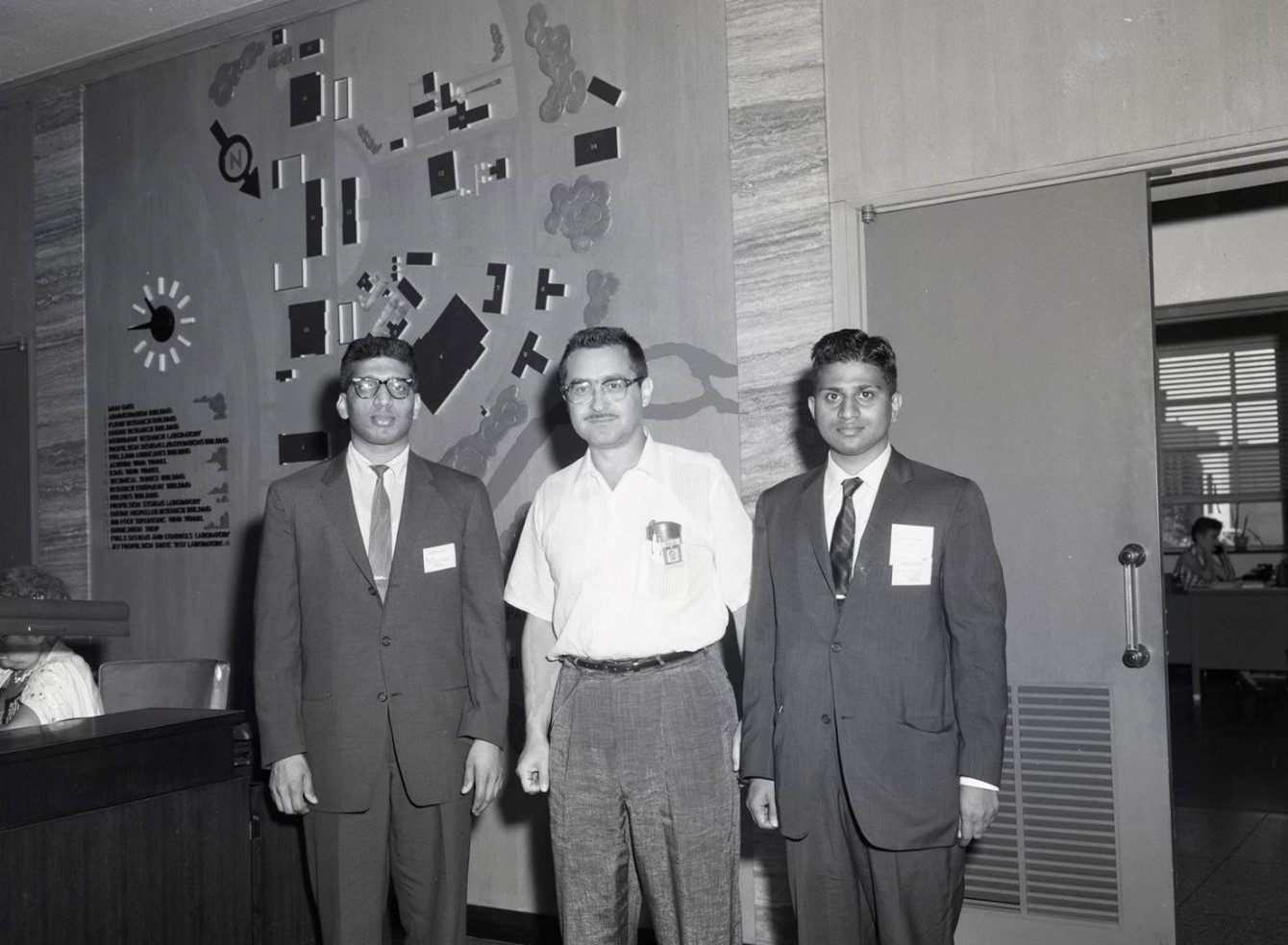 Vintage black and white of researcher and receptionist in the administration building posing with two visitors to the Center.