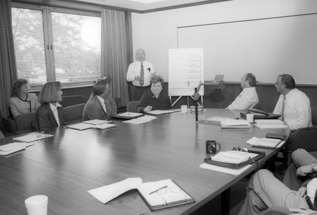 Vintage black and white image of former director Larry Ross meeting with his executive council in 1992.