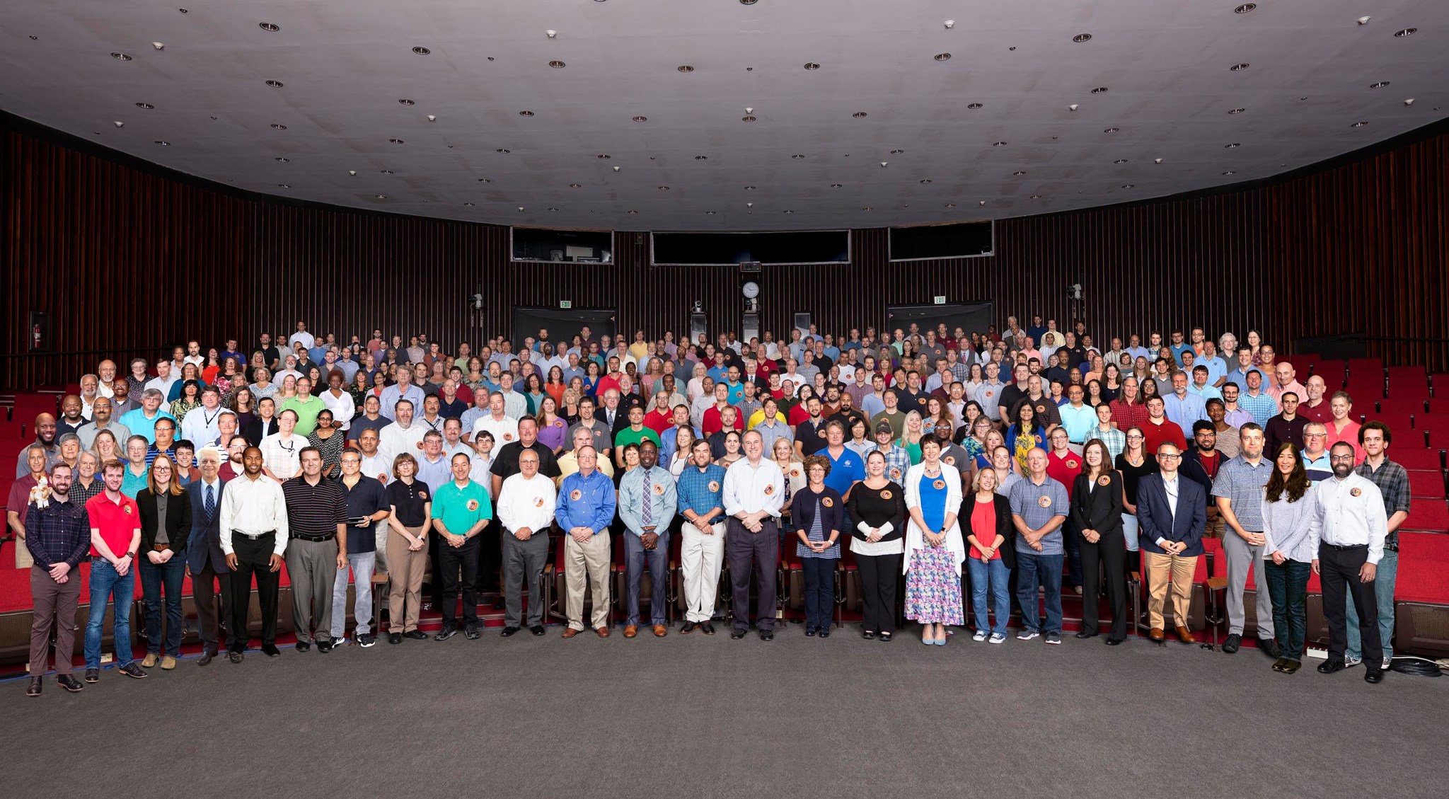 A large group of people pose for a photo inside an auditorium.