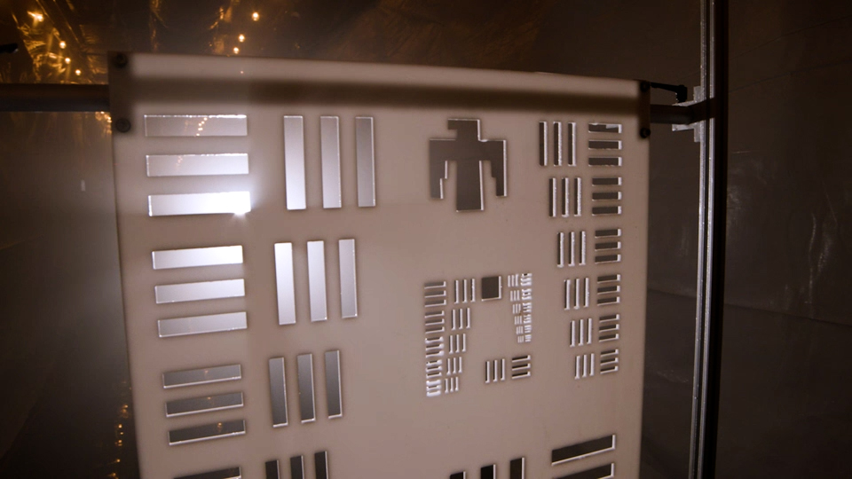A white panel with multiple sets of horizontal and vertical rectangles cut out of it is lit from behind. The rectangles get smaller as you move from group to group.