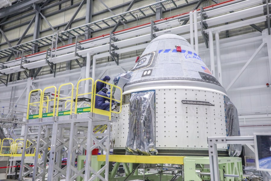 Starliner technicians work on the Orbital Flight Test-2 spacecraft in the high bay of Boeing's Commercial Crew and Cargo Processing Facility at NASA's Kennedy Space Center in Florida on Jan. 13, 2022.