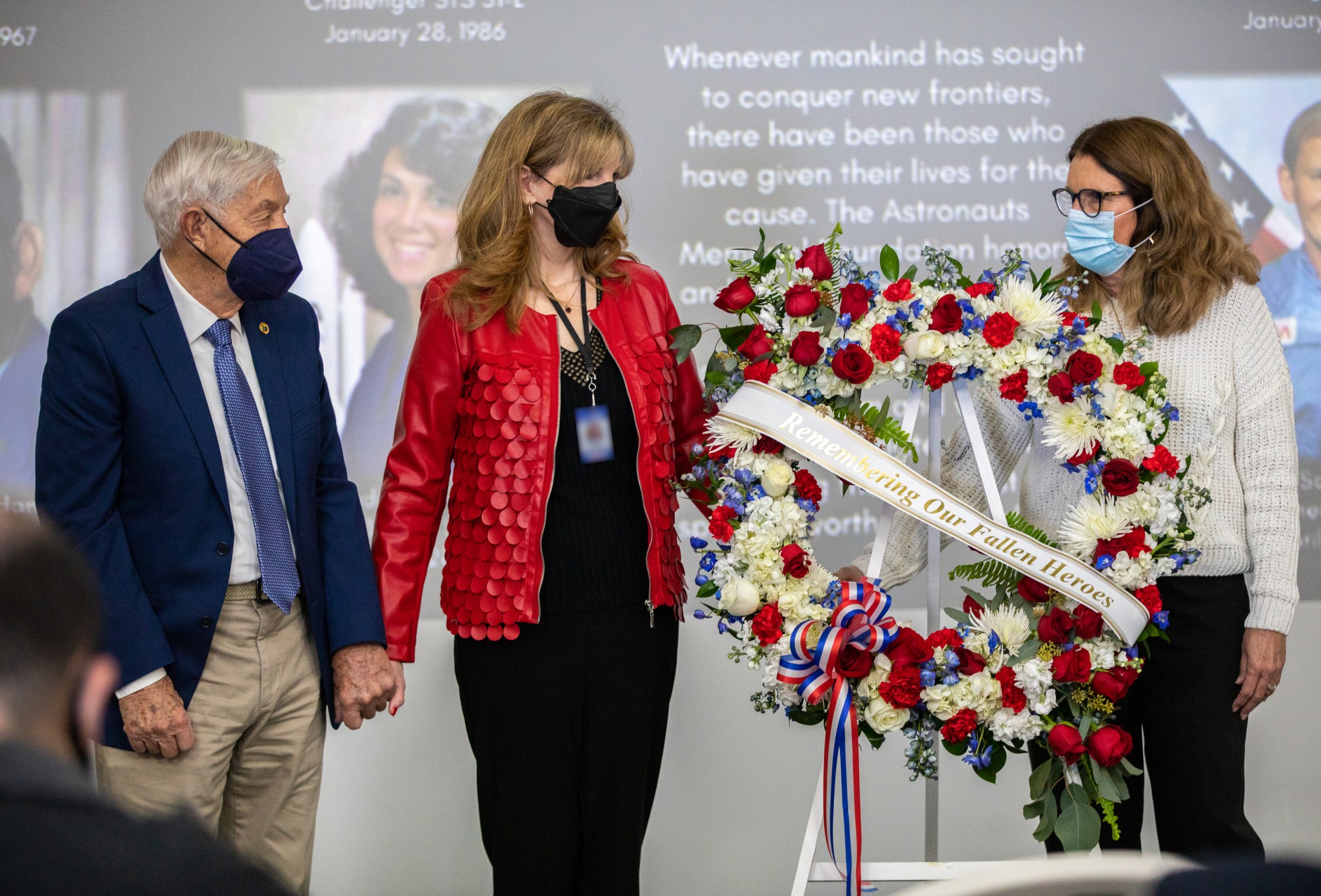 Relatives of fallen astronauts place a wreath in front of on-screen images of those who perished in the pursuit of space exploration during the Day of Remembrance on Jan. 27, 2022 at Kennedy Space Center in Florida.