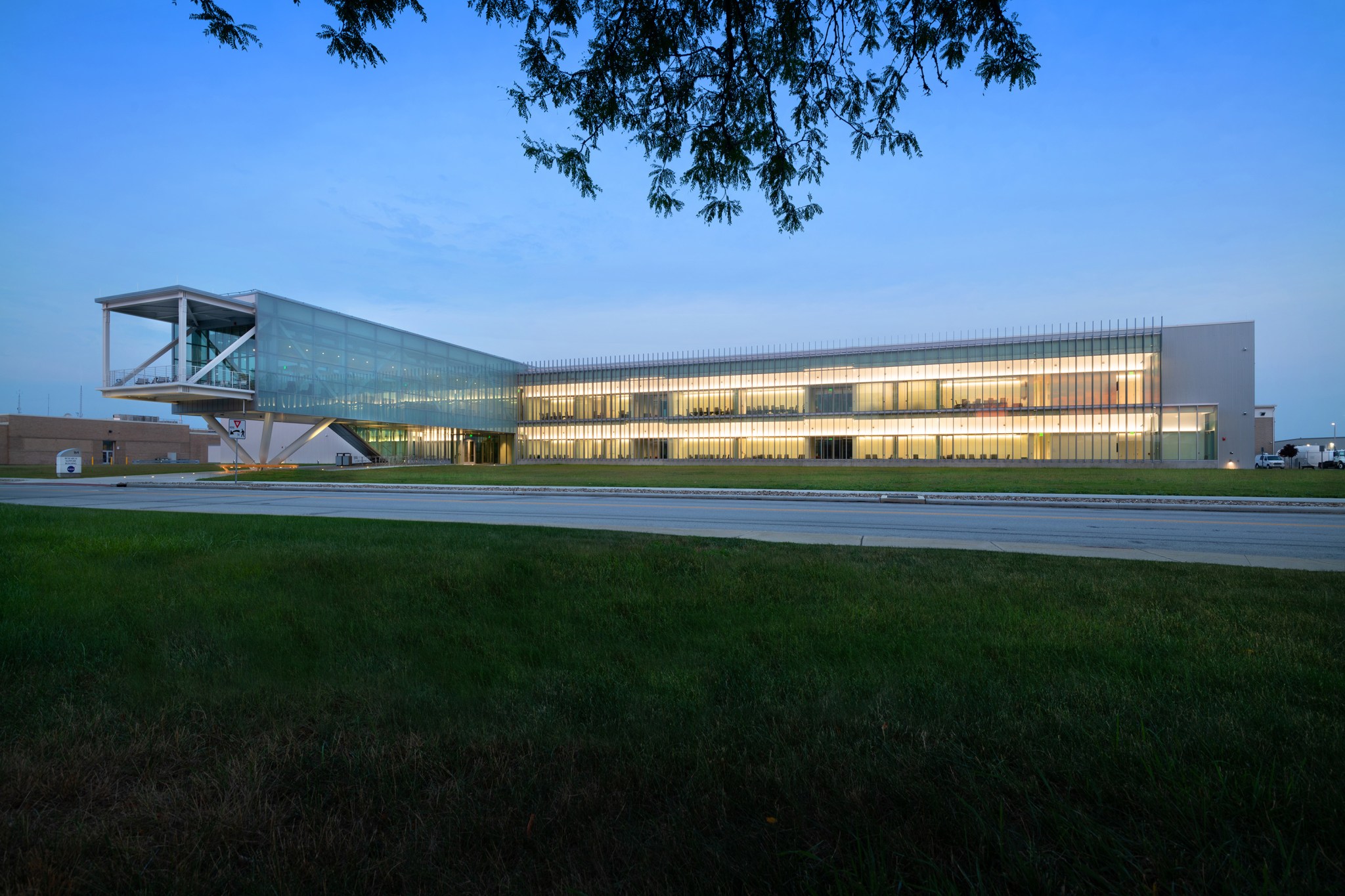 Wide angle view of the new Research Support Building. Interior lights glowing and the sky glowing at sunrise. 