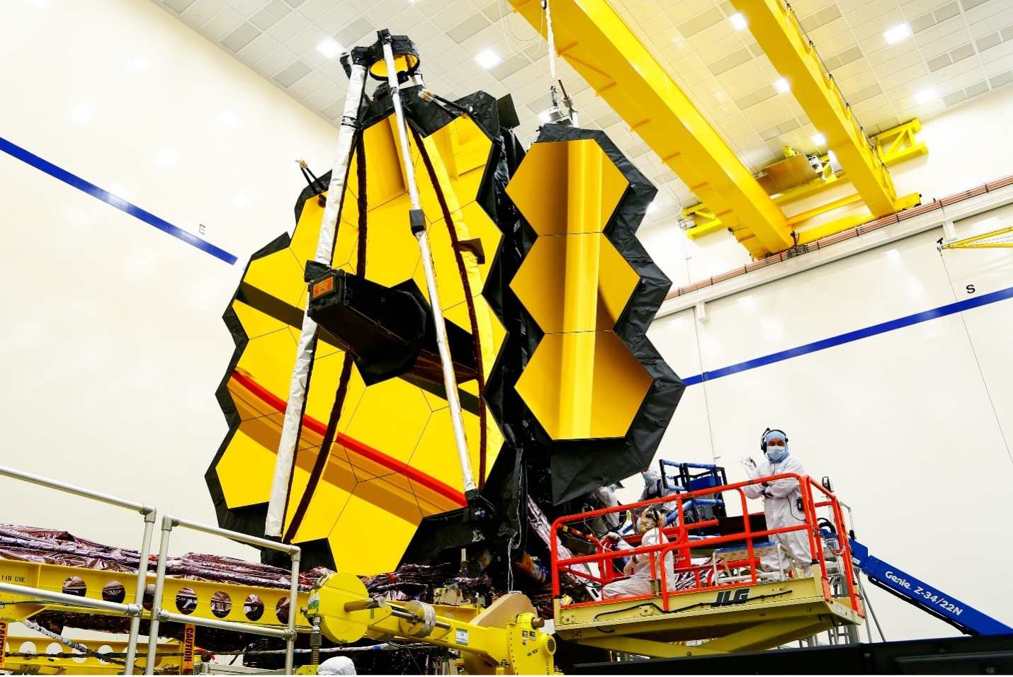 A large telescope in a holding device sitting in a large room at a NASA facility.