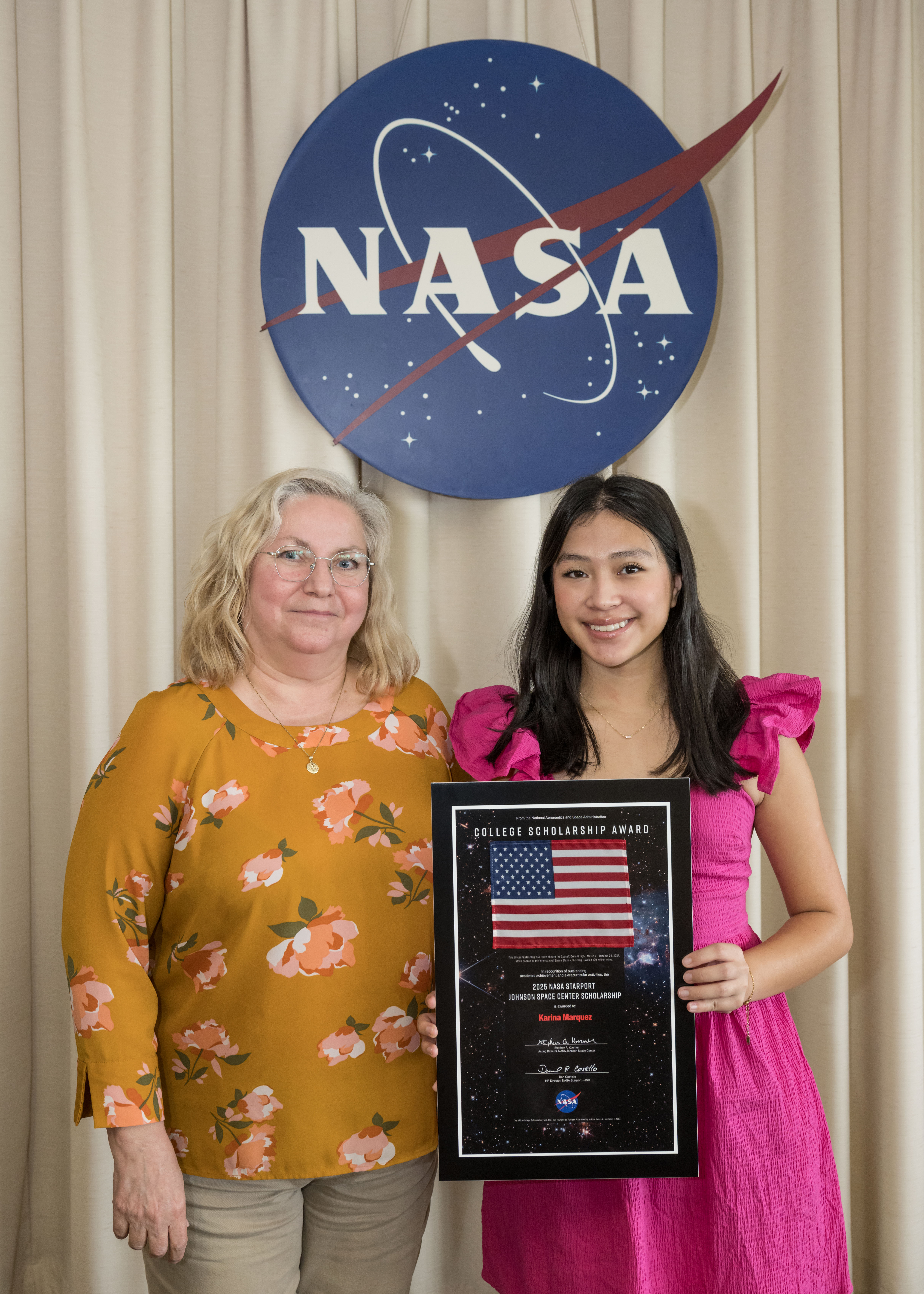 Two women standing in front of the NASA meatball.