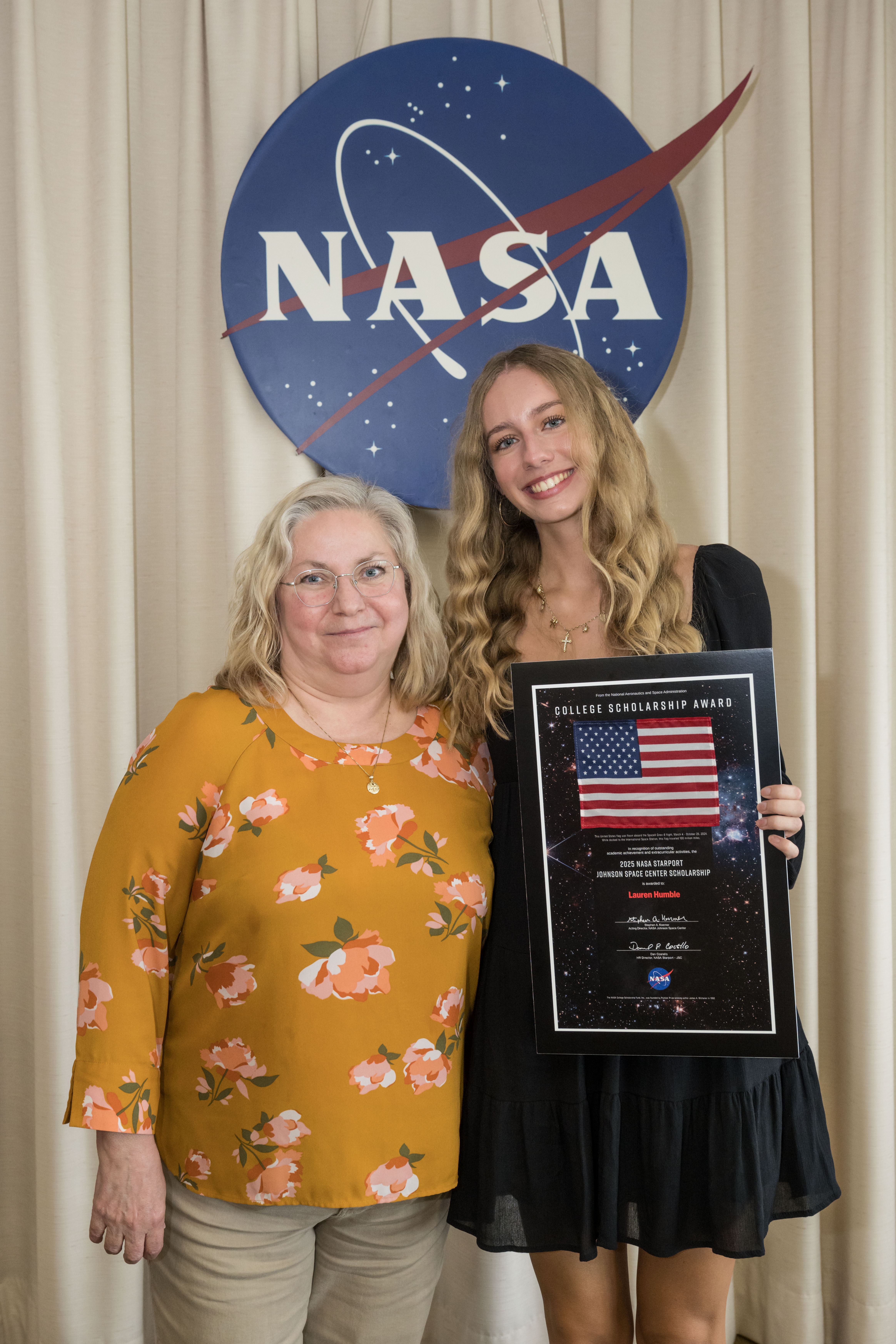 Two women standing in front of the NASA meatball.