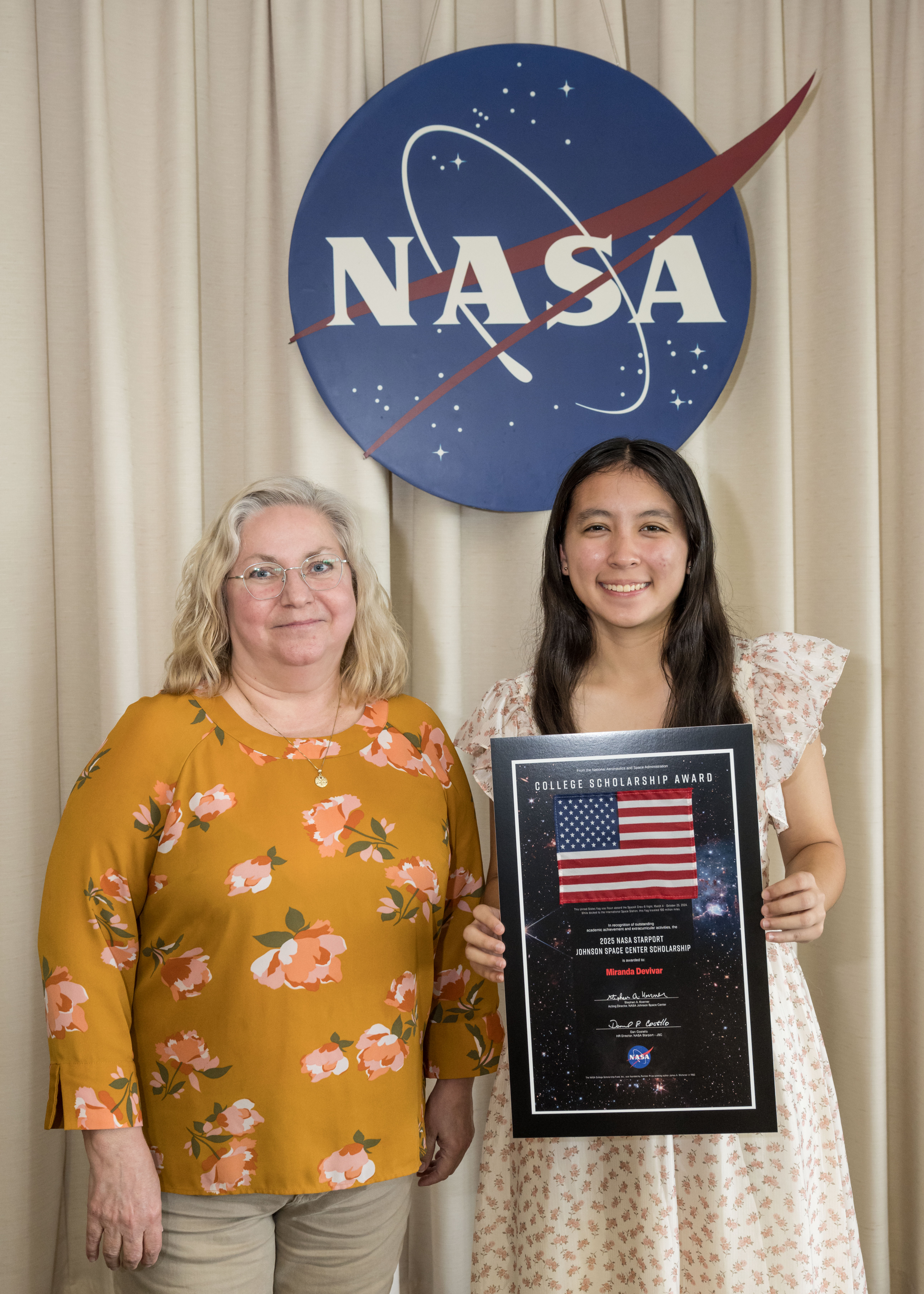 Two women standing in front of the NASA meatball.