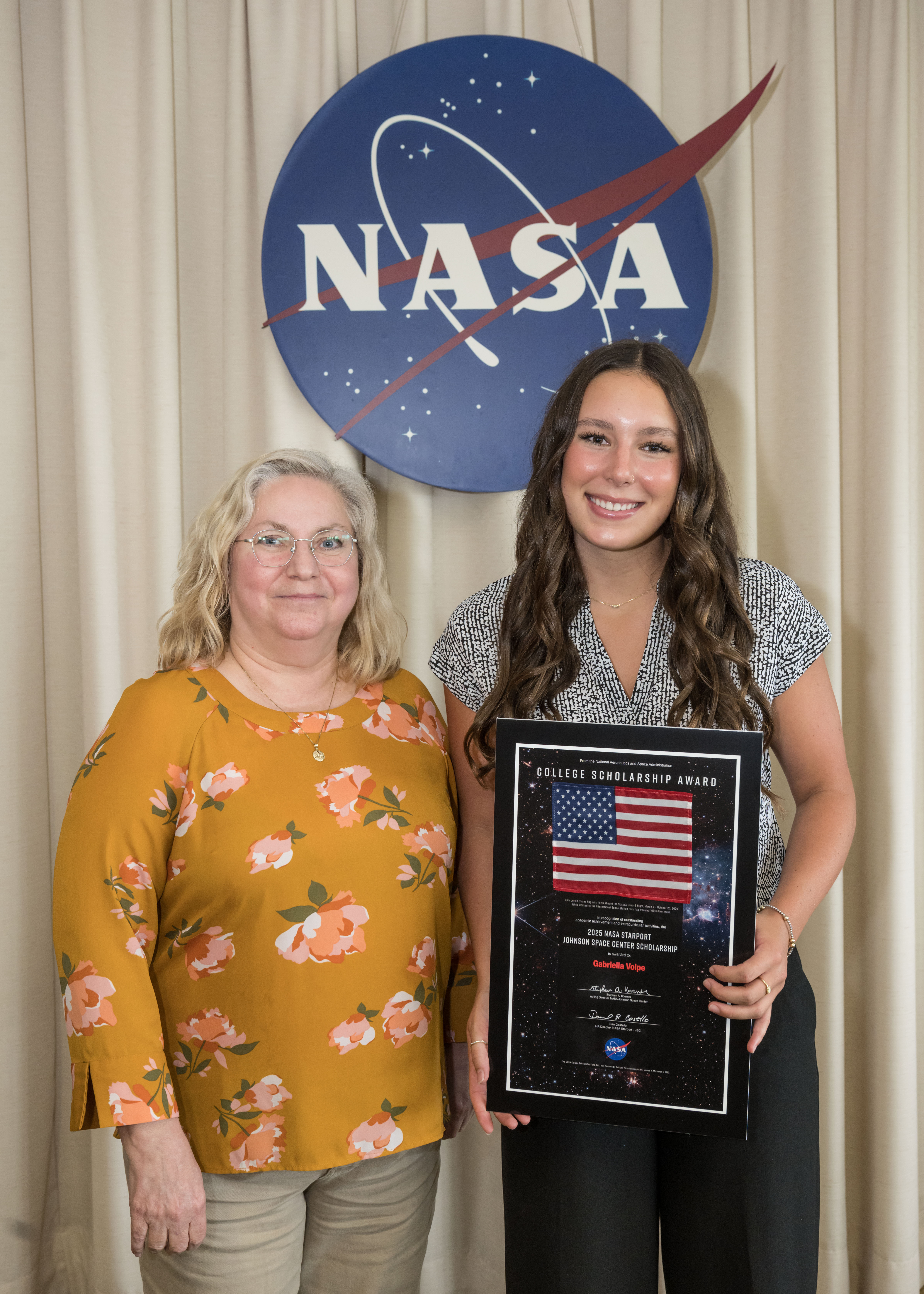 Two women standing in front of the NASA meatball.