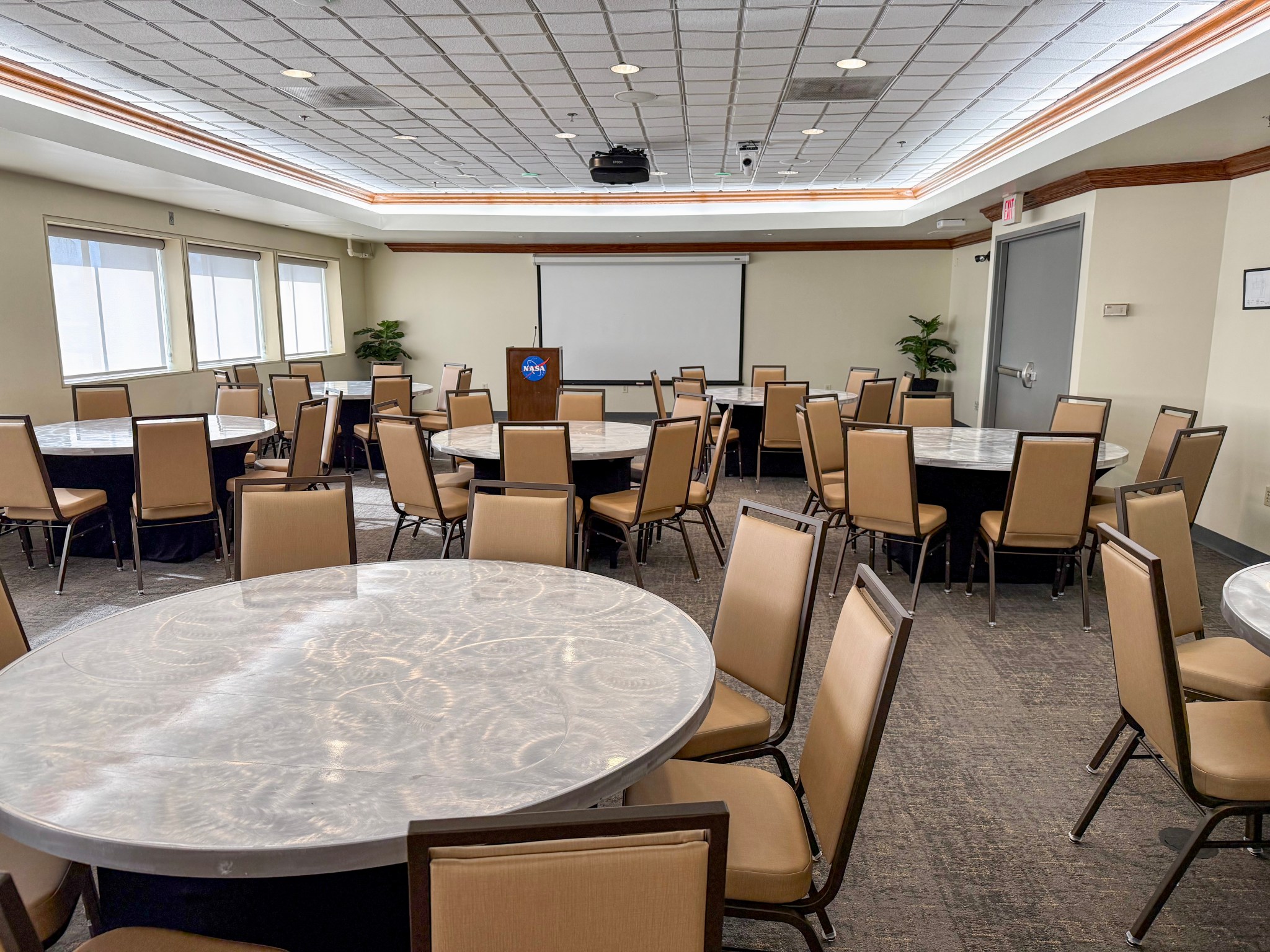 a conference room filled with round, silver-topped tables and beige colored chairs.