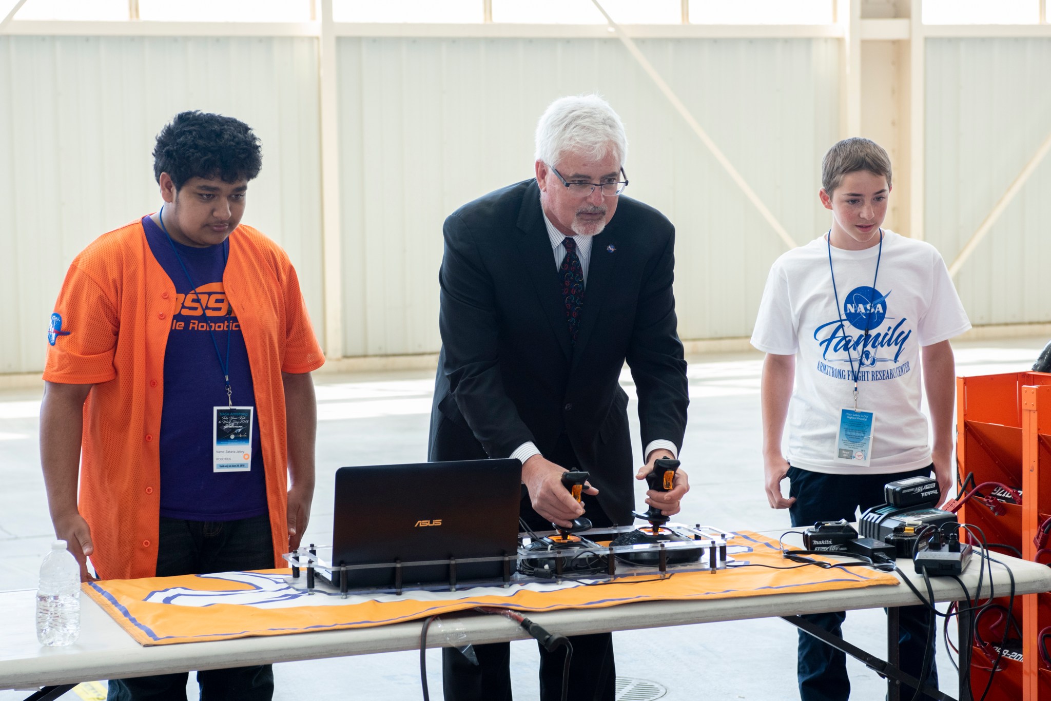 Three people observing a remote controlled robot