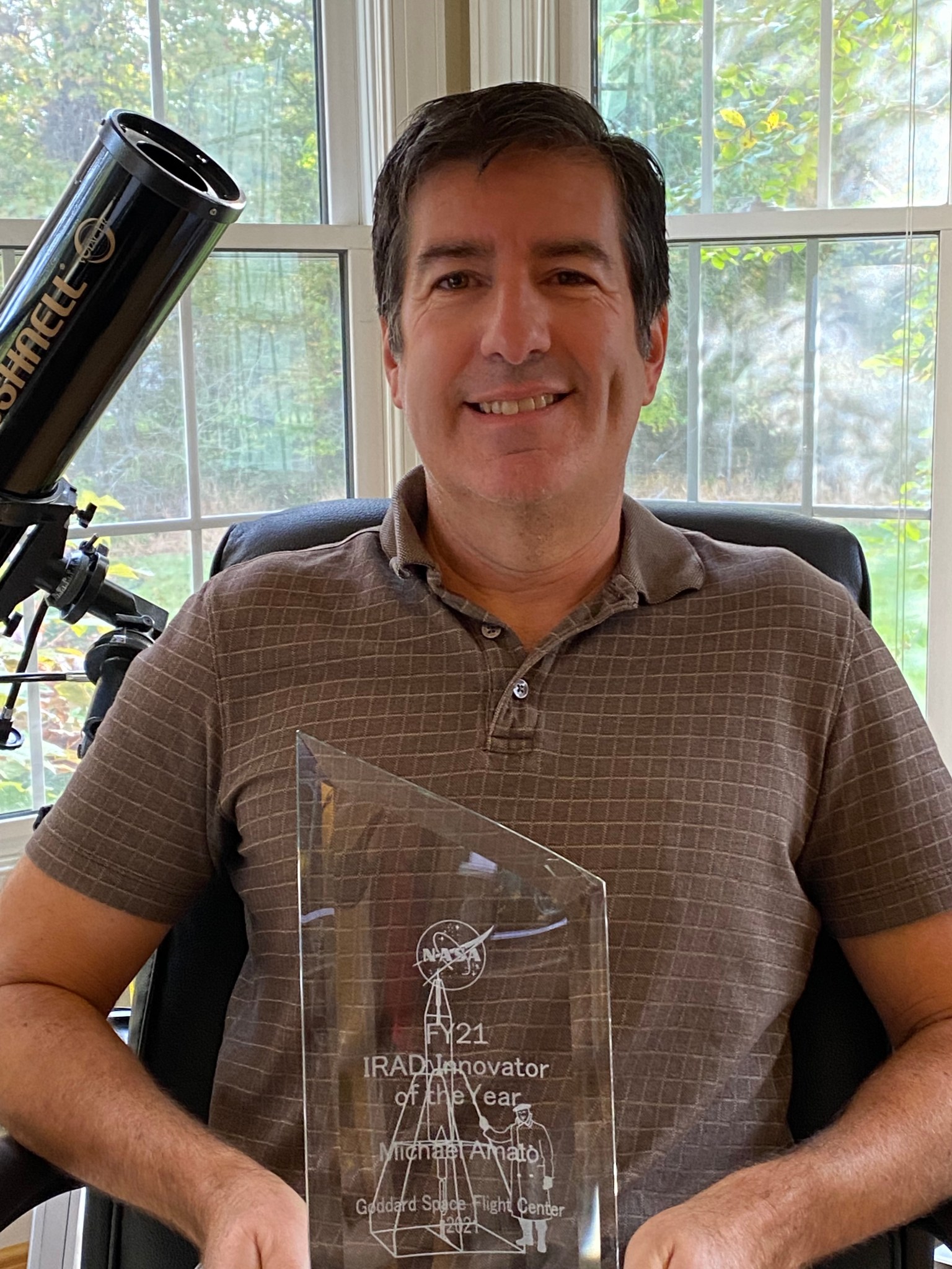 man in front of window  with award
