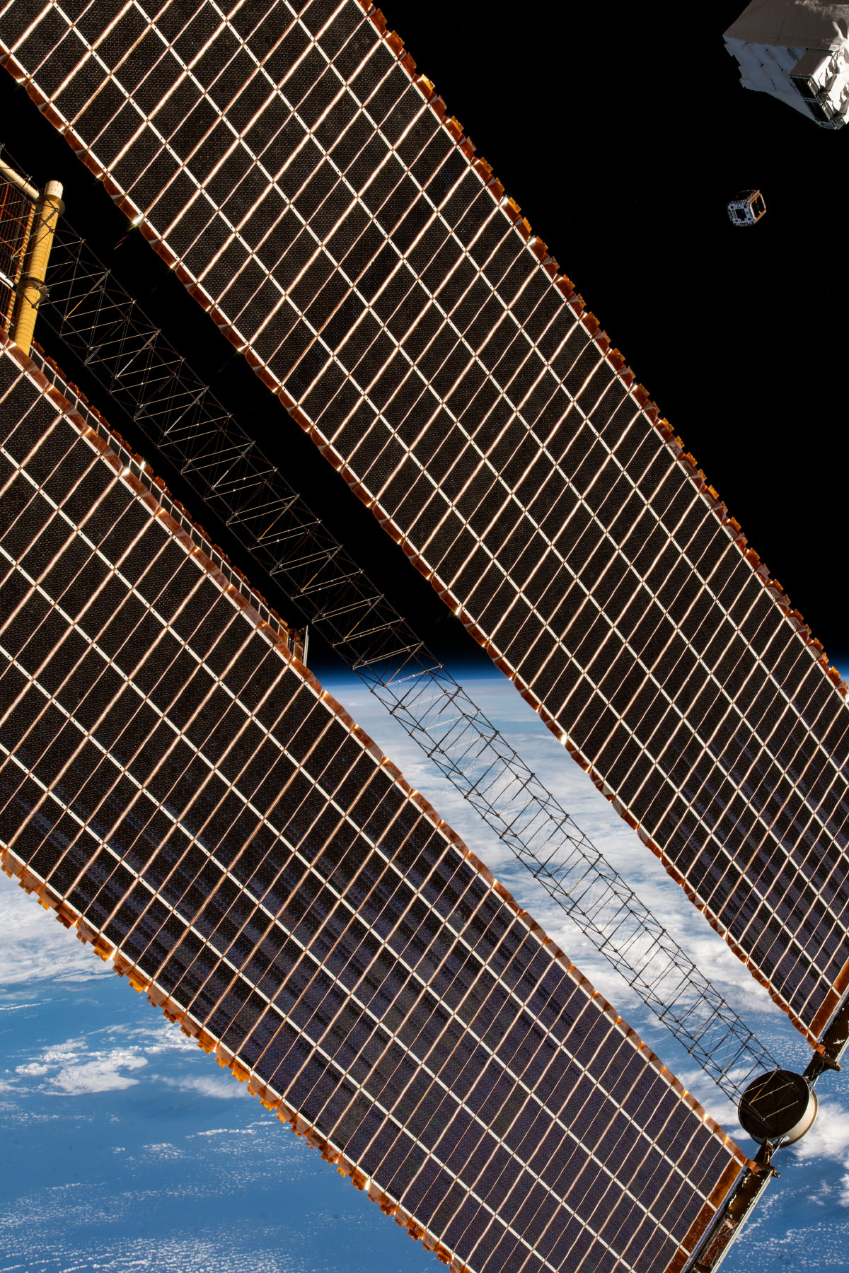 Solar arrays from the International Space Station with a CubeSat in the distance