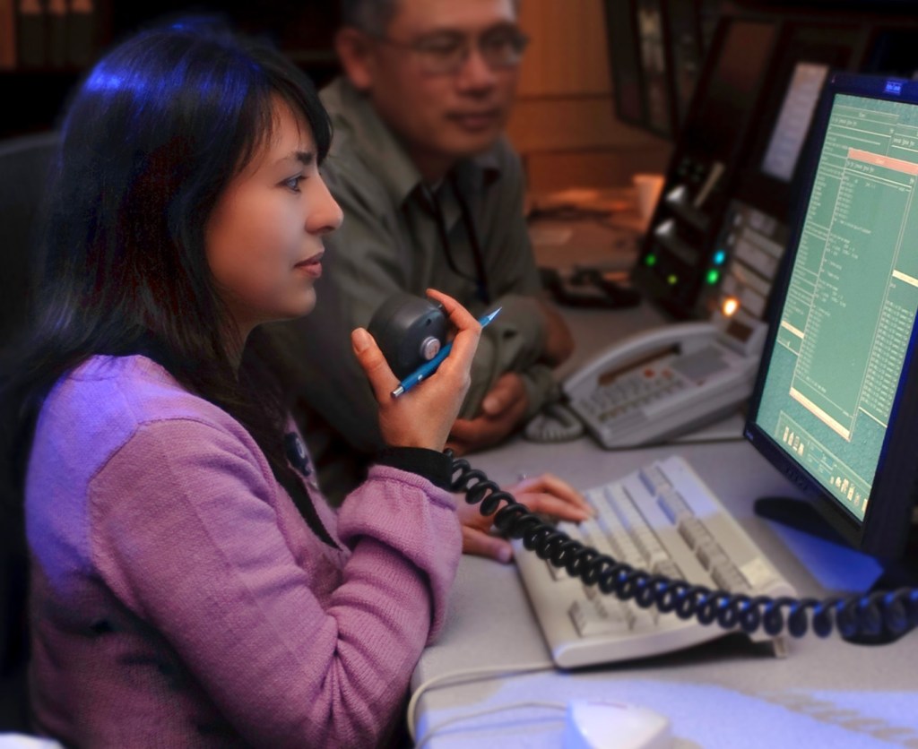 computer operator holding microphone with person watching in background