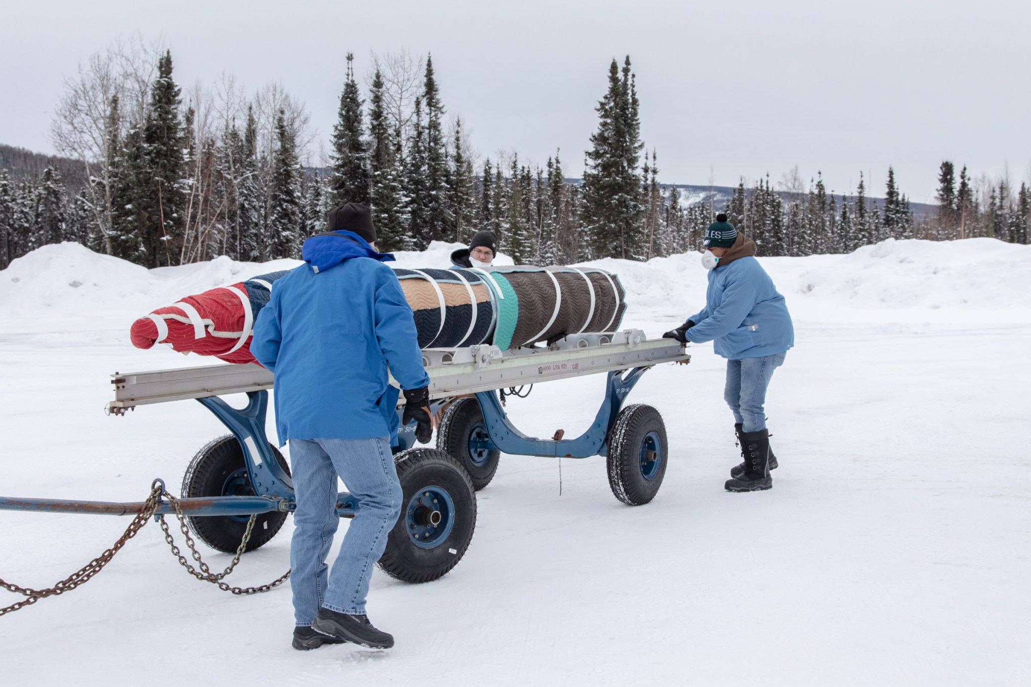Three men rolling out a rocket payload across the snow.