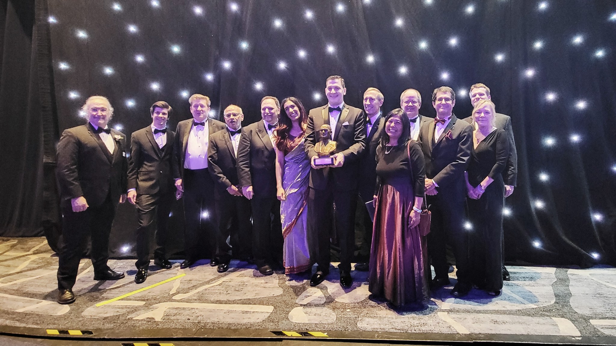 Surrounded by Ingenuity Mars Helicopter team members, Ingenuity lead Teddy Tzanetos holds the Dr. Robert H. Goddard Memorial Trophy that the team received at the National Space Club’s Goddard Memorial Awards Dinner on March 18, 2022.