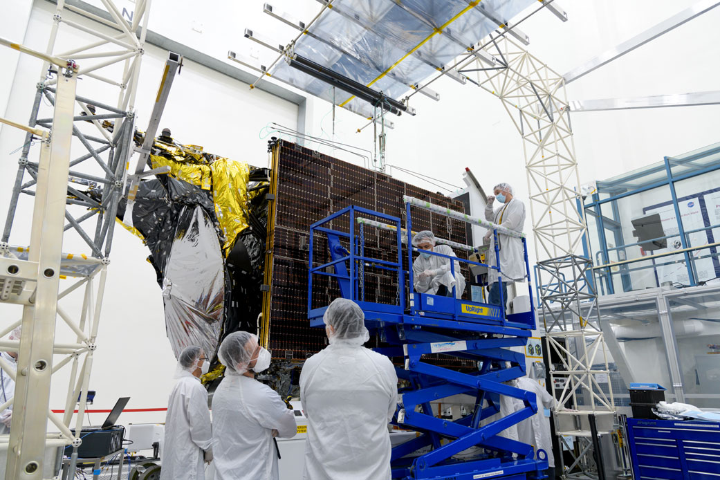 Before a deployment test in a clean room at JPL, engineers examine one of Psyche’s two solar arrays.