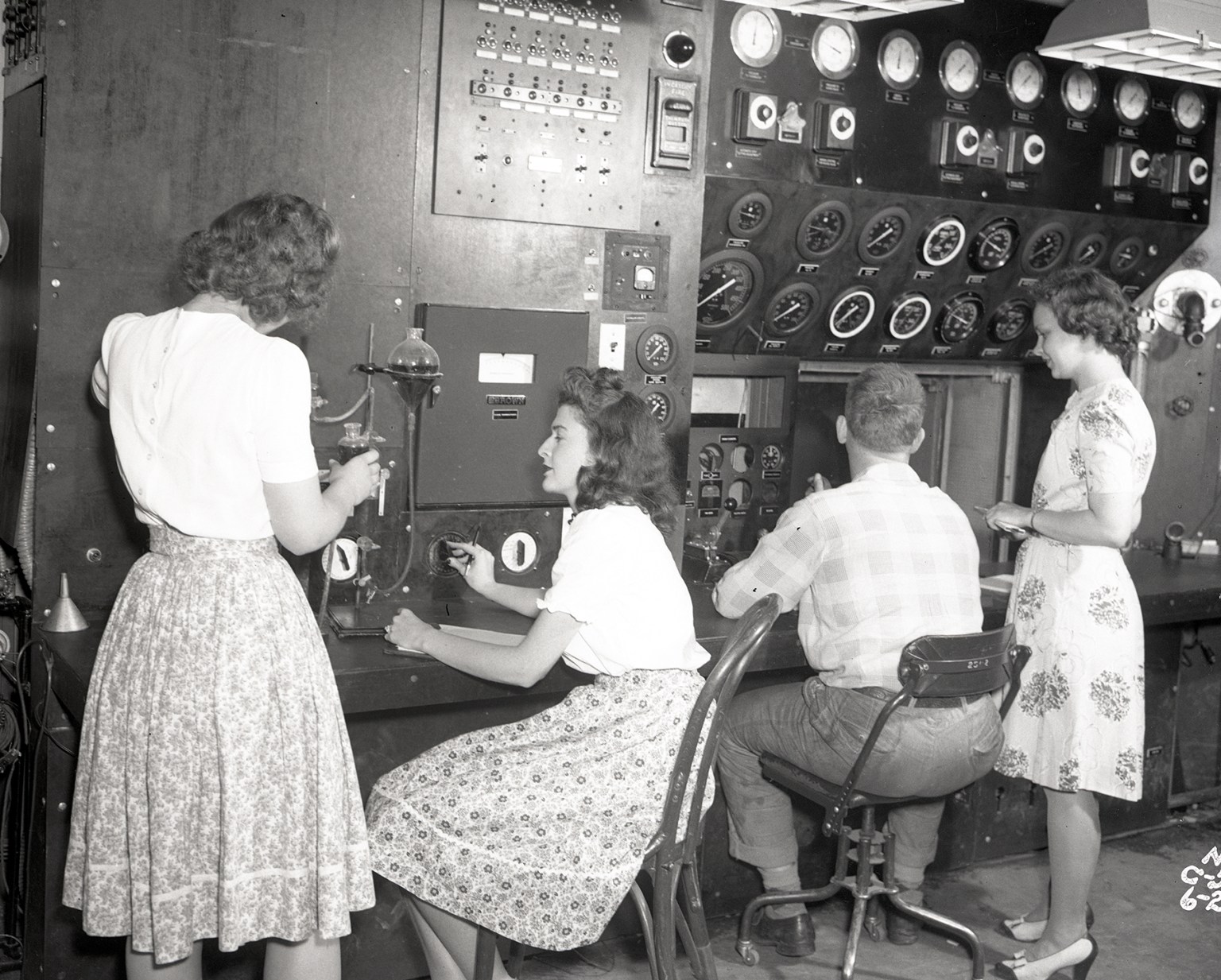 Three women and a man face computers and monitoring equipment.