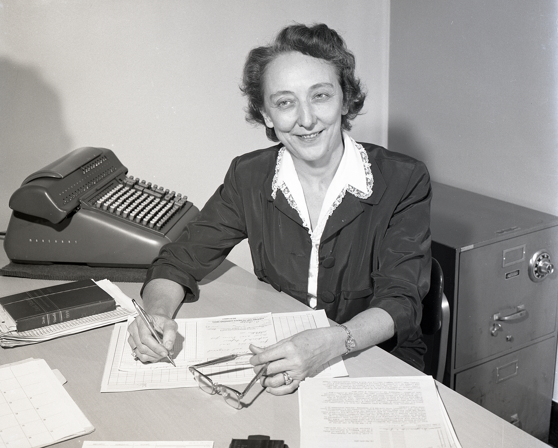 Woman at a desk holds a pencil as she conducts mathematical computations.