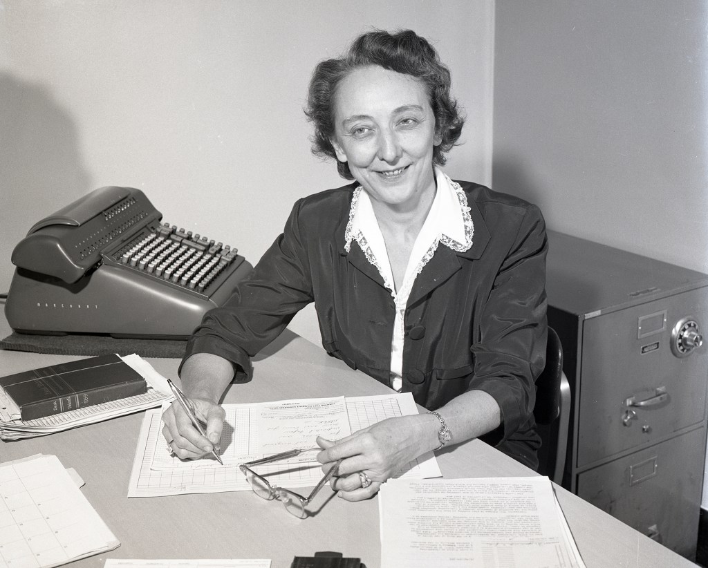 Woman at a desk holds a pencil as she conducts mathematical computations.