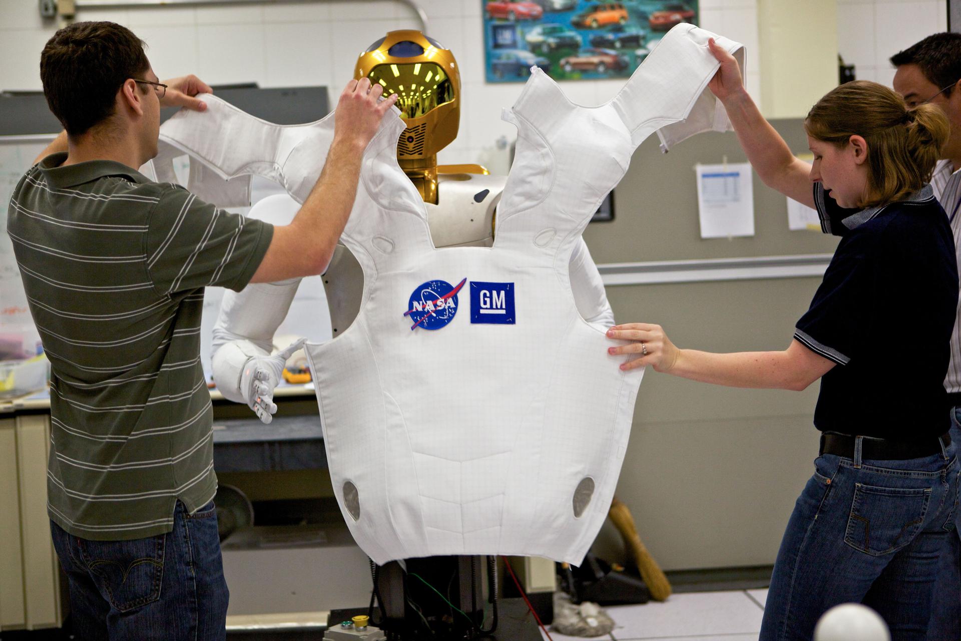 Engineer Court Edmondson and soft goods designer Heather Bibby help Robonaut 2 try on its new flight suit.