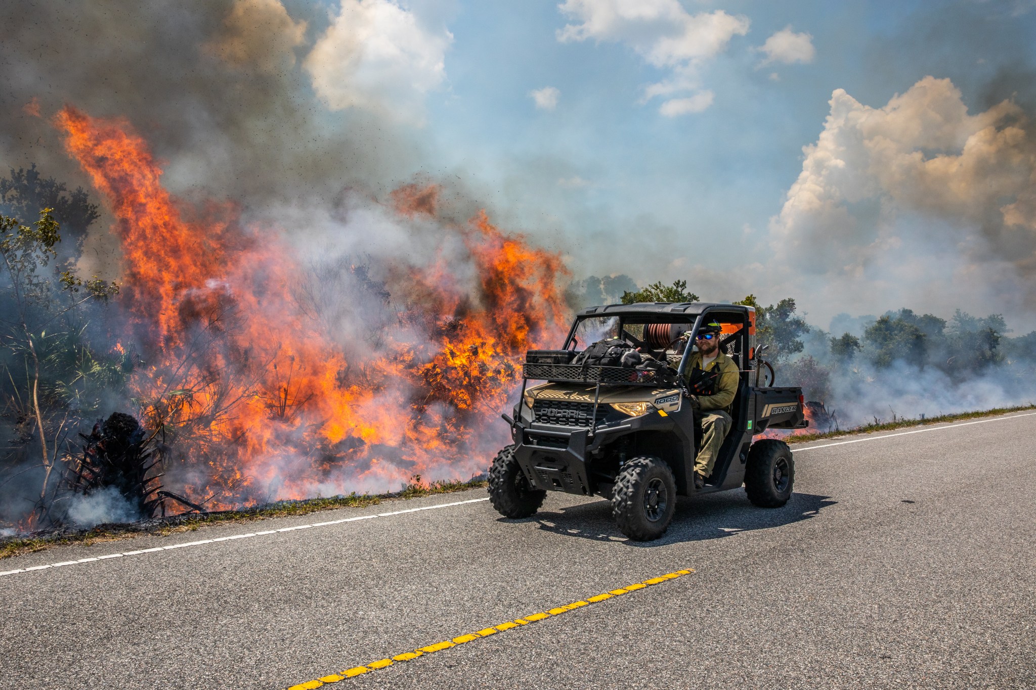 A man in a vehicle near a prescribed burn.