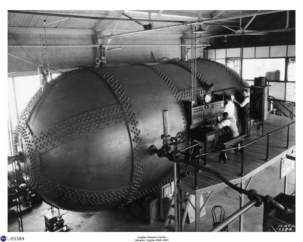 This is a photo of the Variable Density Tunnel during testing. Photographed on May 5, 1931, the man at far right is thought to be Harold J. "Cannonball" Turner, Langley’s longtime safety officer. This view of the VDT clearly shows the layout of the tunnel's surroundings, as well as its plumbing and power needs.