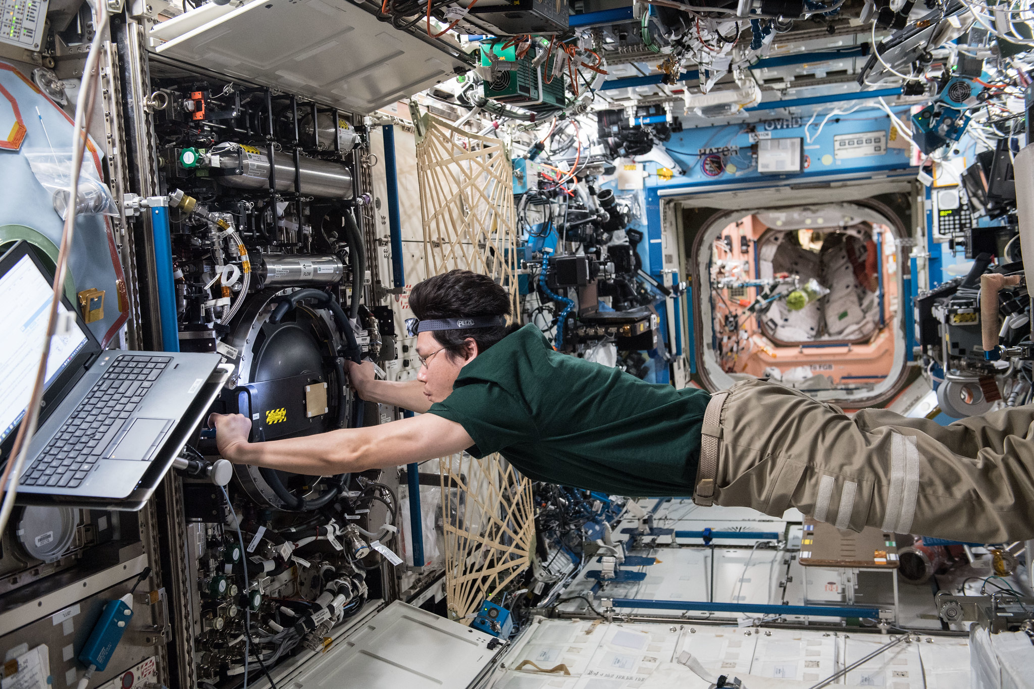 Floating astronaut examines camera inside the space station.
